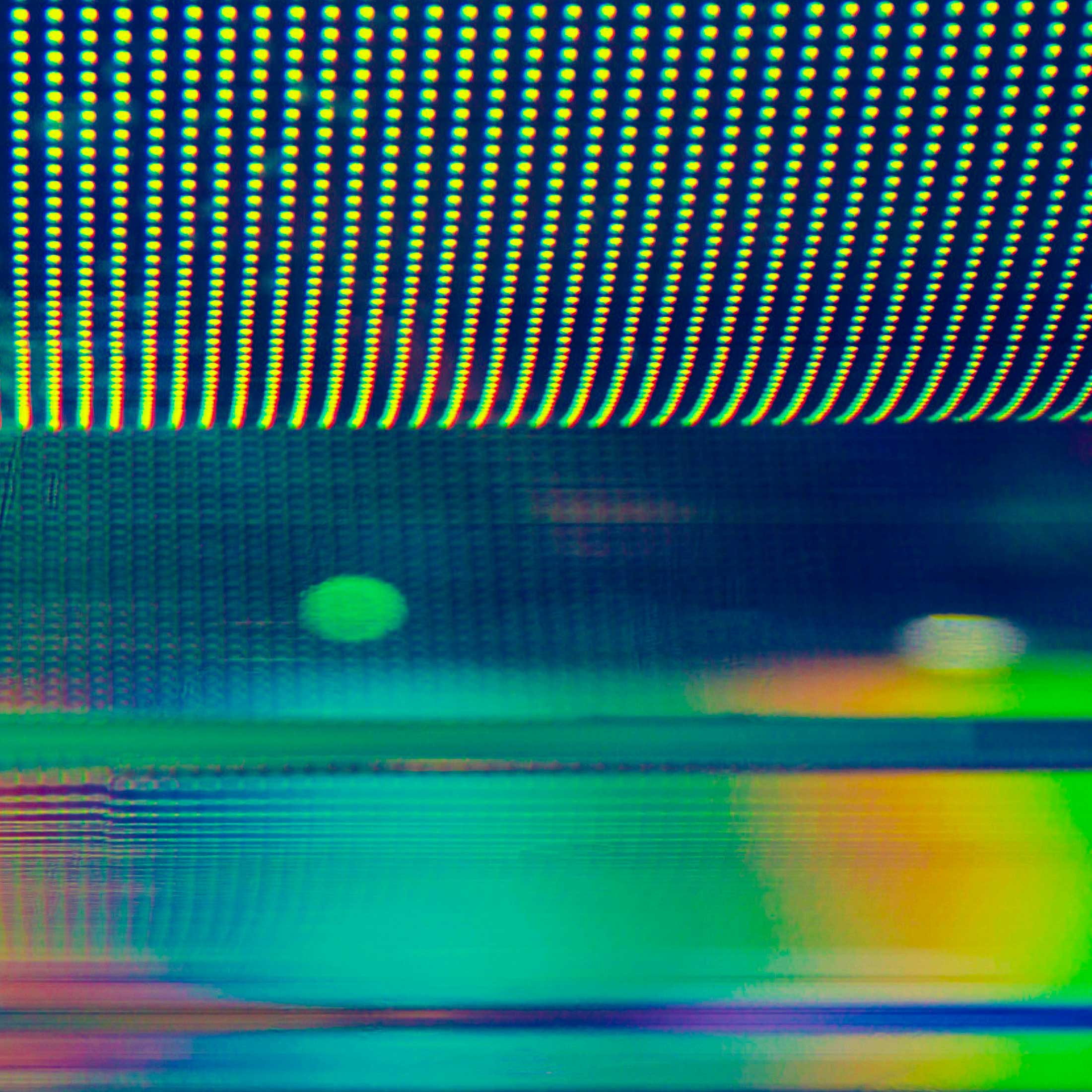 Yellow, blue and green abstract light photograph, shows dots of lights plus moving layer lights at the bottom.