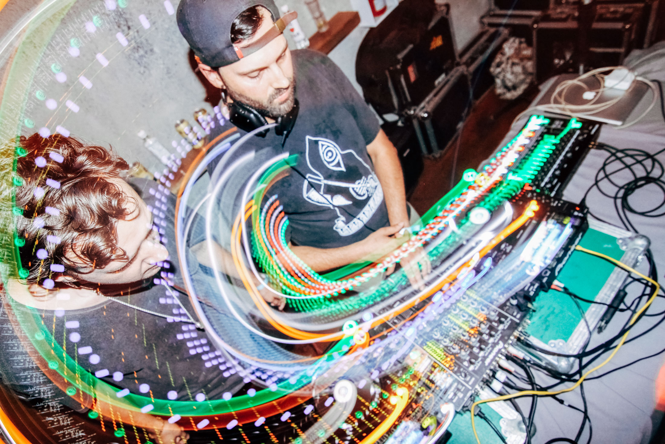 2 DJs on the left, showing them mixing and turning dials, the lights are also long exposed and they show a long round movement, leading to a dramatic photograph.