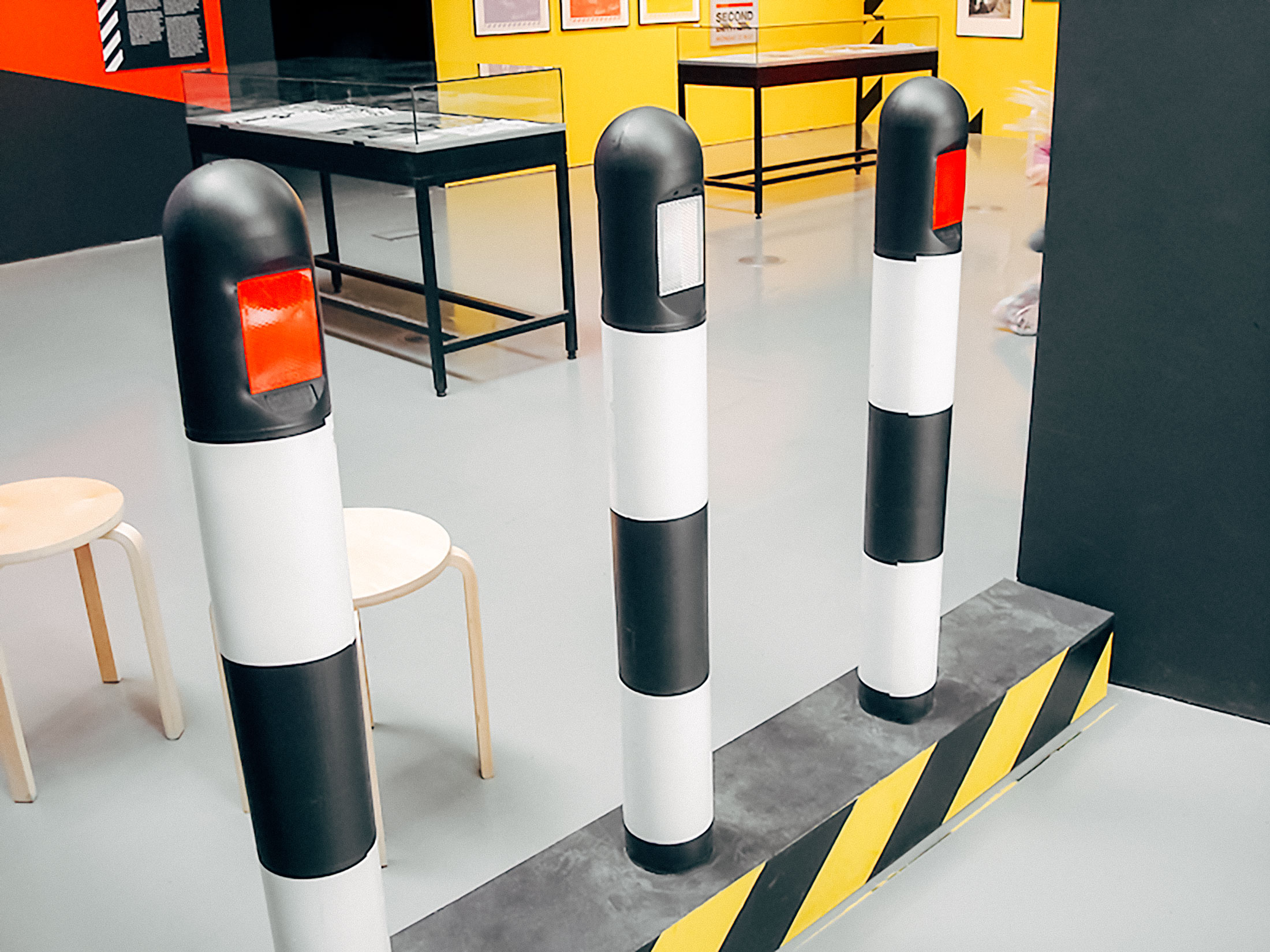 3 road bollards, black striped, from the original Haçienda nightclub in Manchester. They are up for sale in an art gallery.