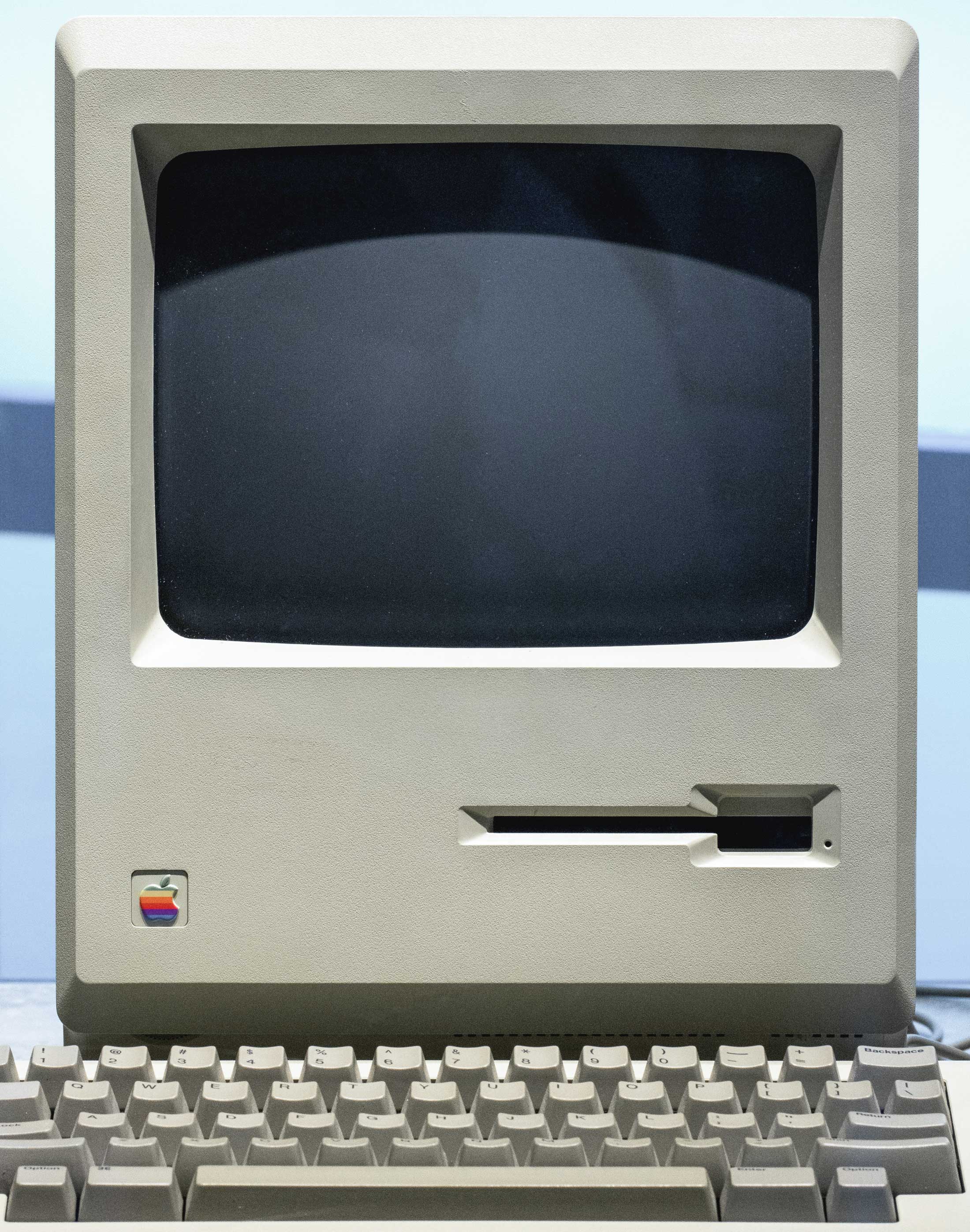 Front on photograph of the Macintosh 128K released in 1984, shows the small darkish yellow screen, then keyboard below.